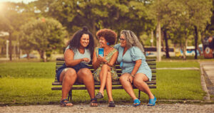 Três mulheres sentadas em banco ao ar livre