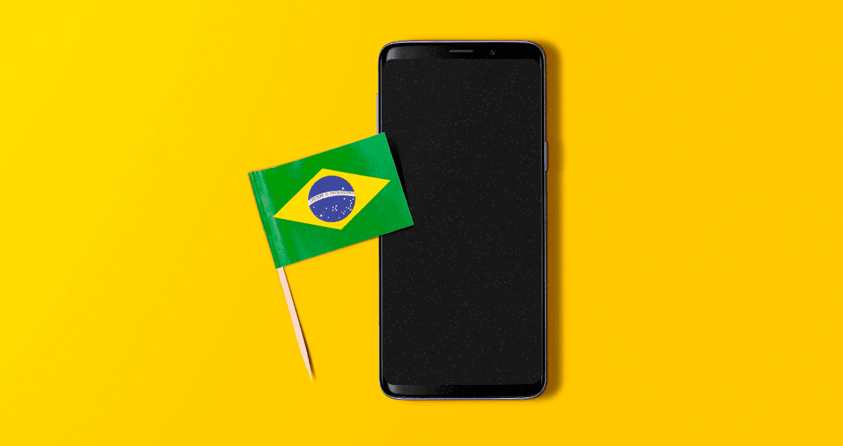 Celular com bandeira do Brasil ao lado sobre fundo amarelo