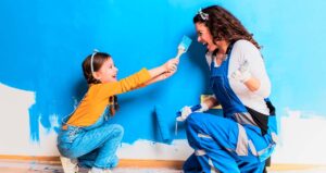 Criança e mulher pintando parede de casa e dando risada