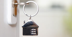Chaveiro de casa pendurado em chave colocada na fechadura de uma porta