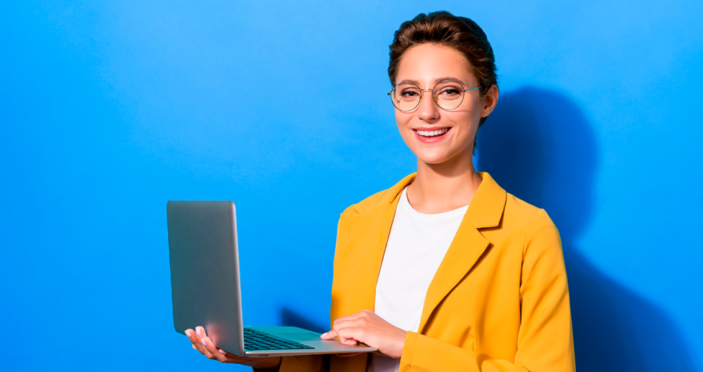 Mulher segurando computador e sorrindo em frente a fundo azul
