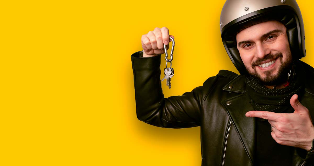 Homem de capacete segurando chaves na mão em frente a fundo amarelo