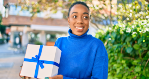 Mulher segurando caixa de presente branca com laço azul