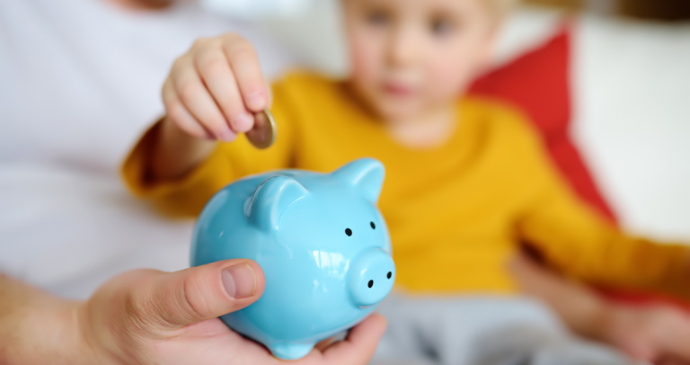 Criança colocando moeda em porquinho azul