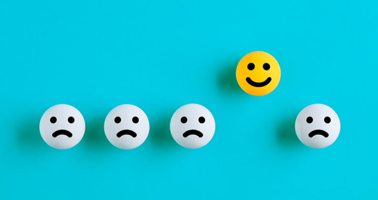 Emojis brancos tristes enfileirados com um emoji feliz amarelo em destaque