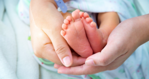 Mãos segurando pés de recém-nascido