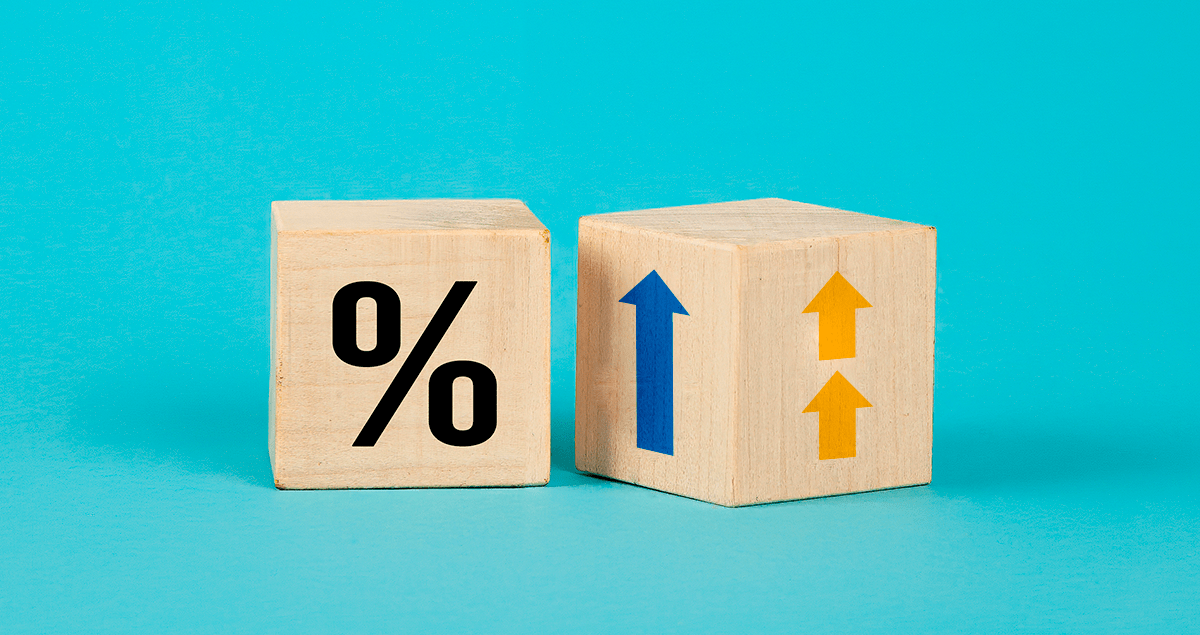 Dicas para redução da taxa de juros do financiamento imobiliário 1 Dois cubos de madeira com símbolos de porcentagem e setas para cima