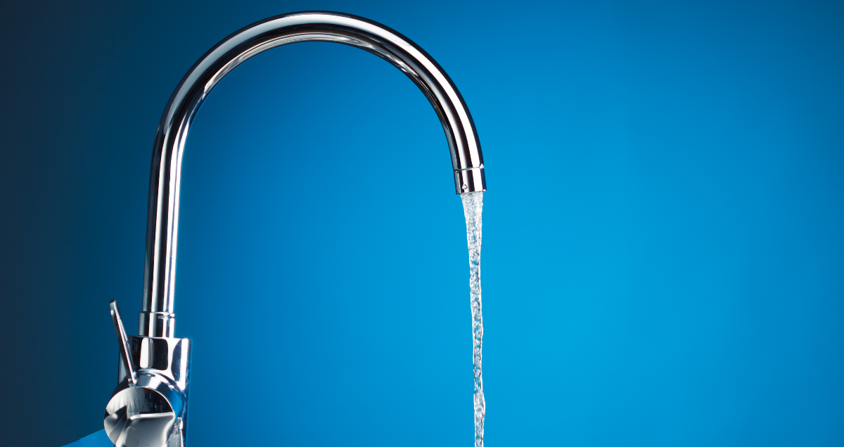 Torneira aberta em frente a fundo azul