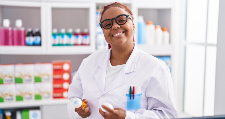 Mulher de jaleco branco sorrindo em farmácia segurando frascos de remédios