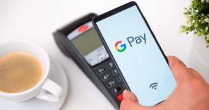 Logo do Google Pay em tela de celular em frente a maquininha