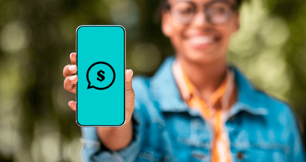 Pessoa segurando celular com símbolo de conversa e dinheiro na frente