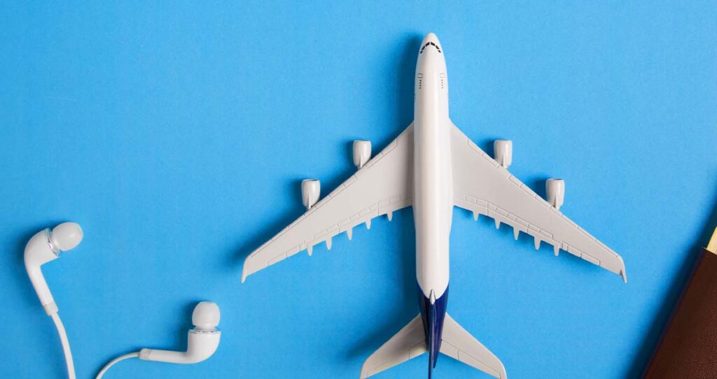 Miniatura de avião e fone de ouvido brancos em cima de fundo azul claro