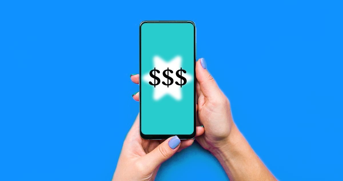 Mãos segurando celular e na tela se vê três cifrões