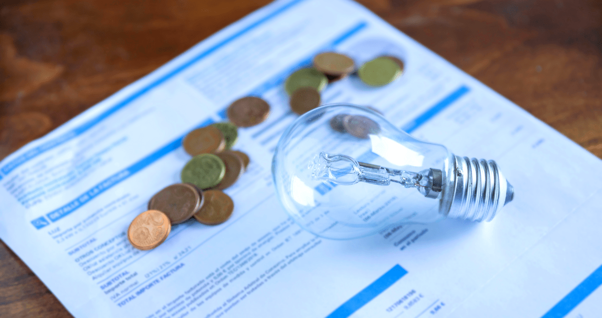 Lâmpada e moedas em cima de conta de luz