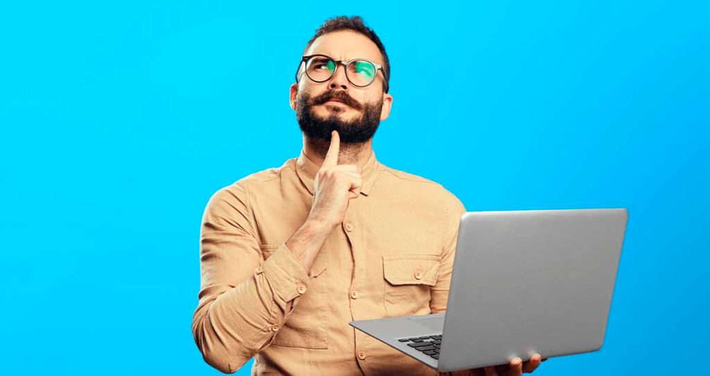 Homem em dúvida segurando computador em frente a fundo azul