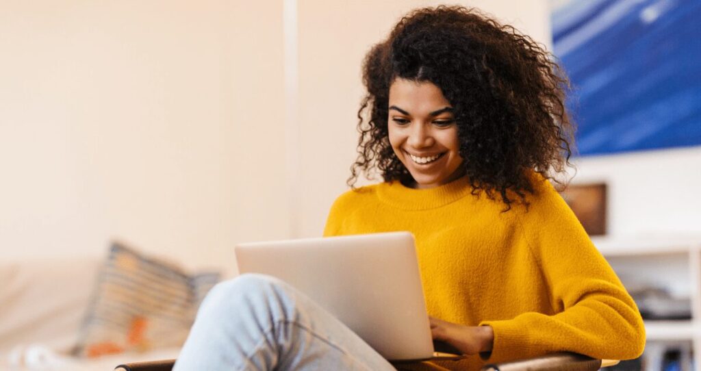 Mulher sorrindo com computador no colo