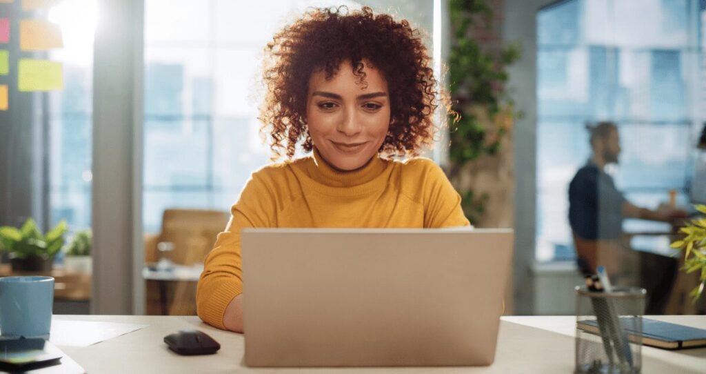 Mulher sorrindo em frente a computador