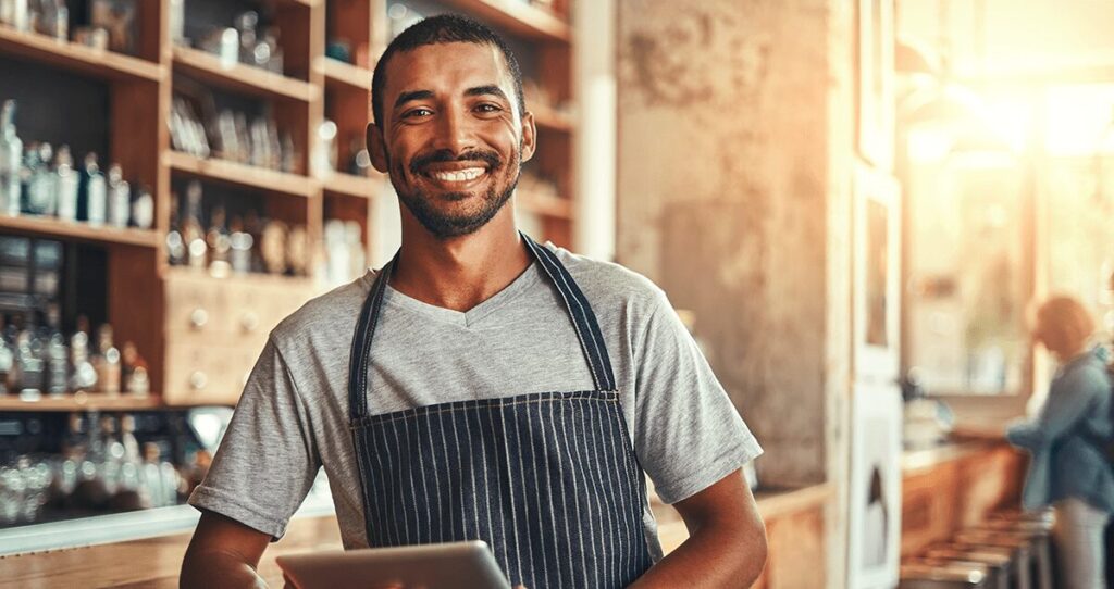 Homem de avental segurando tablet e sorrindo