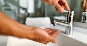 Pessoa lavando as mãos em pia