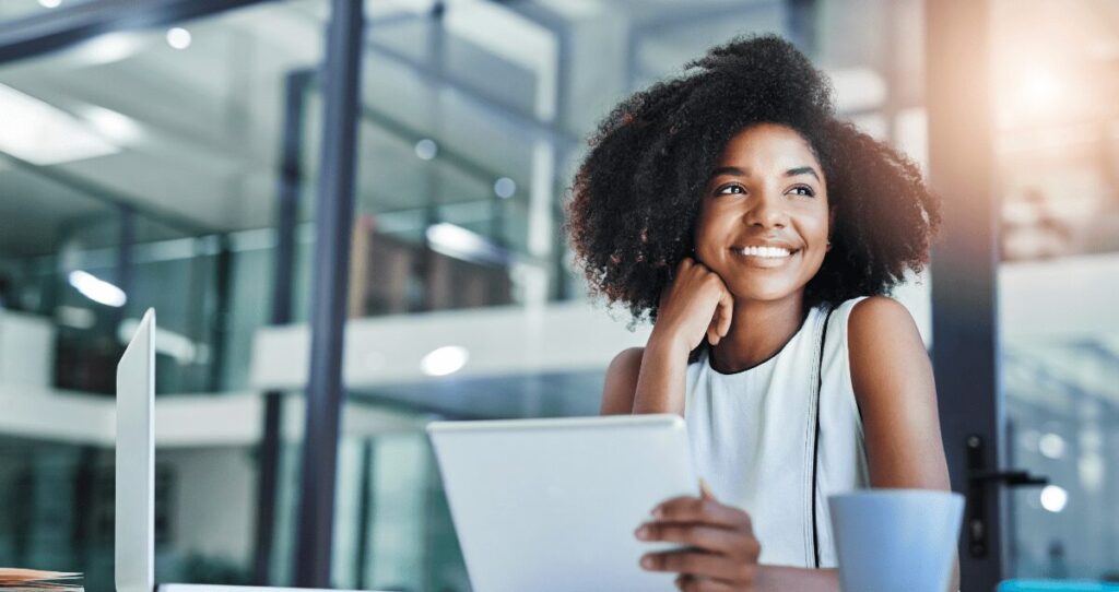 Mulher sorrindo em frente a computador e olhando para o lado