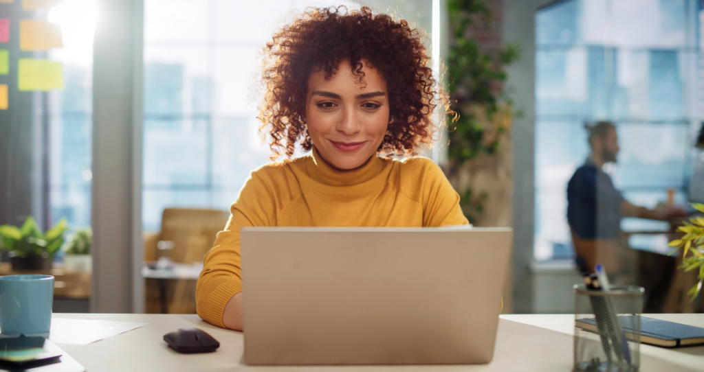 Mulher de blusa amarela em frente a computador