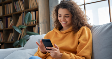 Mulher sorrindo segurando celular nas mãos