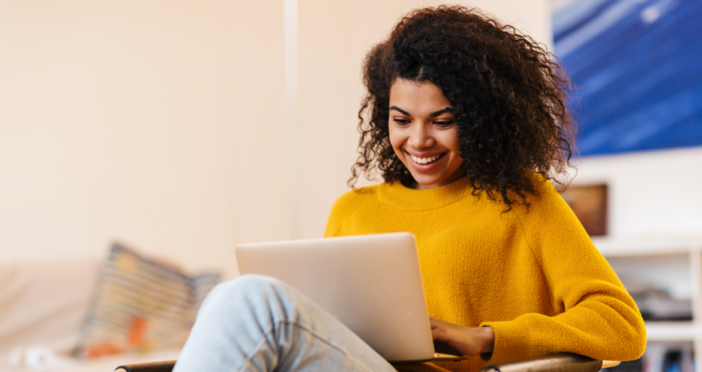 Mulher com computador no colo sorrindo