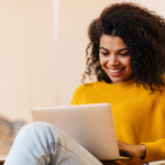 Mulher com computador no colo sorrindo