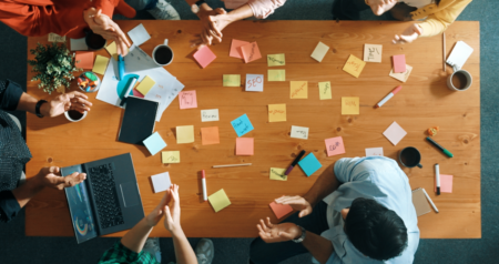 Pessoas ao redor de mesa com post its coloridos em cima