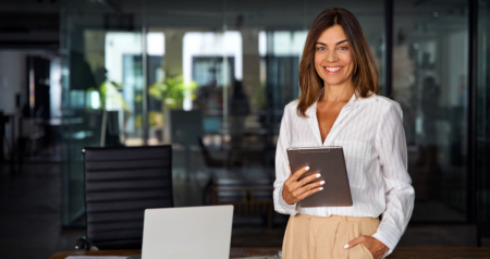 Mulher segurando tablet em escritório e sorrindo