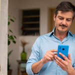 Homem mexendo em celular azul