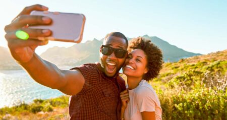 Homem e mulher tirando selfie à beira do mar