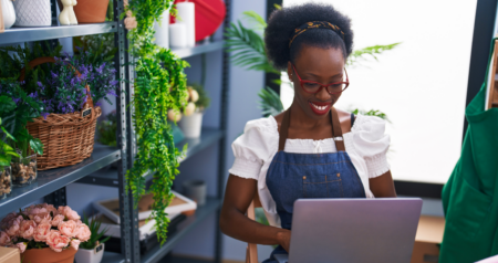 Mulher com plantas ao redor mexendo no computador