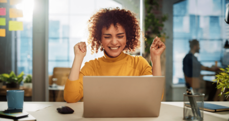 Mulher comemorando em frente a computador