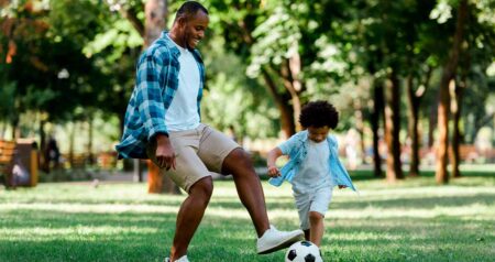 Homem e criança jogando bola em parque