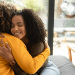 Duas mulheres se abraçando em sala