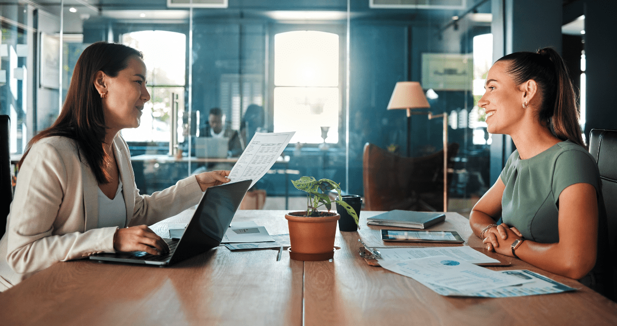 Duas mulheres uma em frente a outra em mesa de escritório