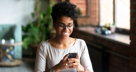 Mulher sorrindo segurando celular nas mãos