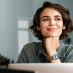 Mulher em frente a computador sorrindo olhando para o lado