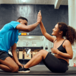 Treinador e aluna batendo as mãos em academia