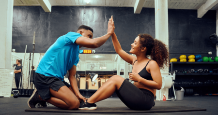 Treinador e aluna batendo as mãos em academia