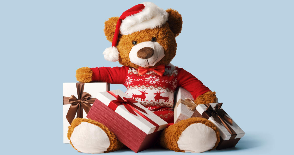 Ursinho de pelúcia vestido com suéter de Natal com presentes ao redor