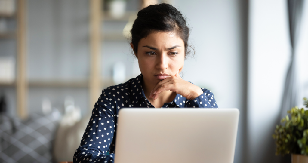 Mulher olhando para computador com semblante preocupado